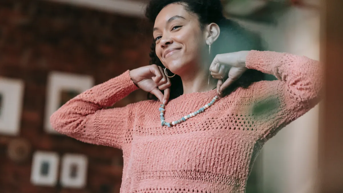 Woman smiling while adjusting a necklace