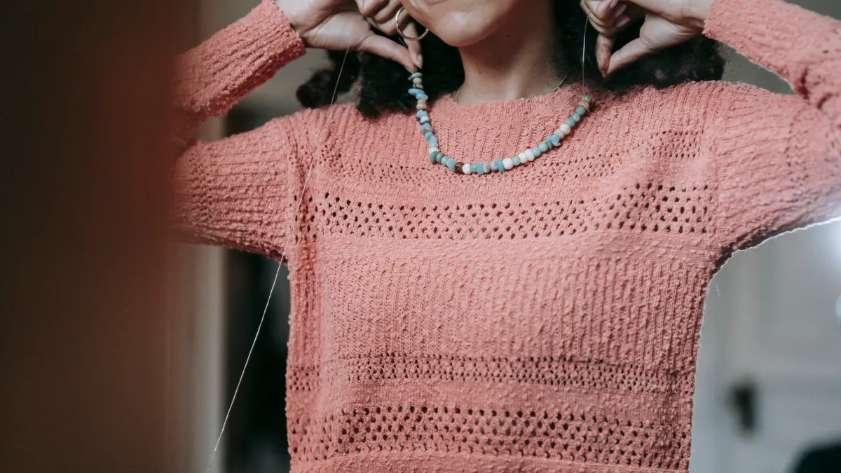 Woman holding a beaded necklace at her neckline