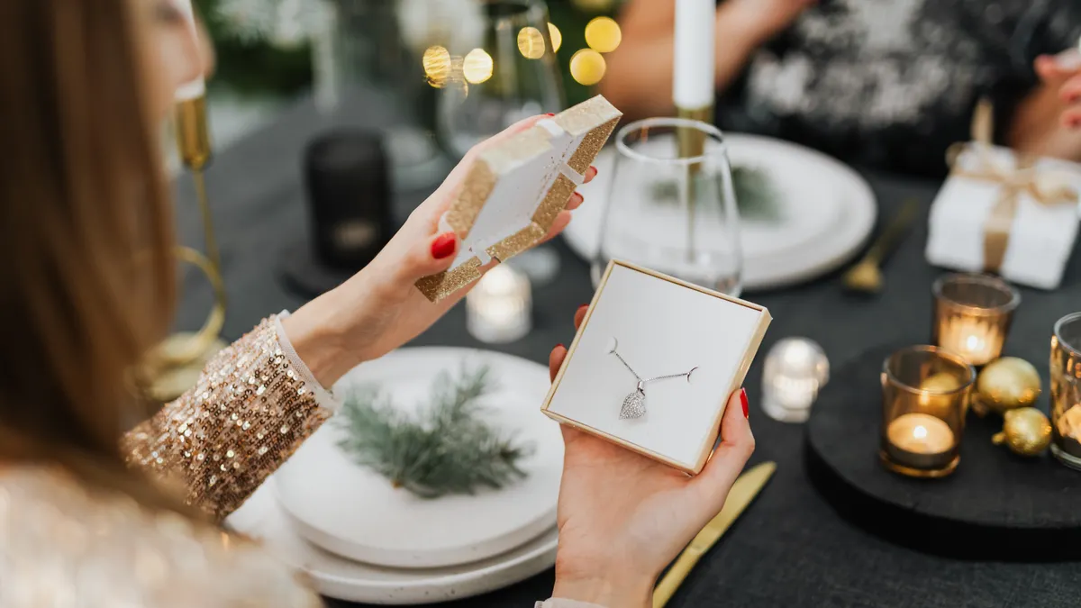 Initial pendant necklaces: how to choose a letter pendant that feels personal Person holding an open necklace gift box