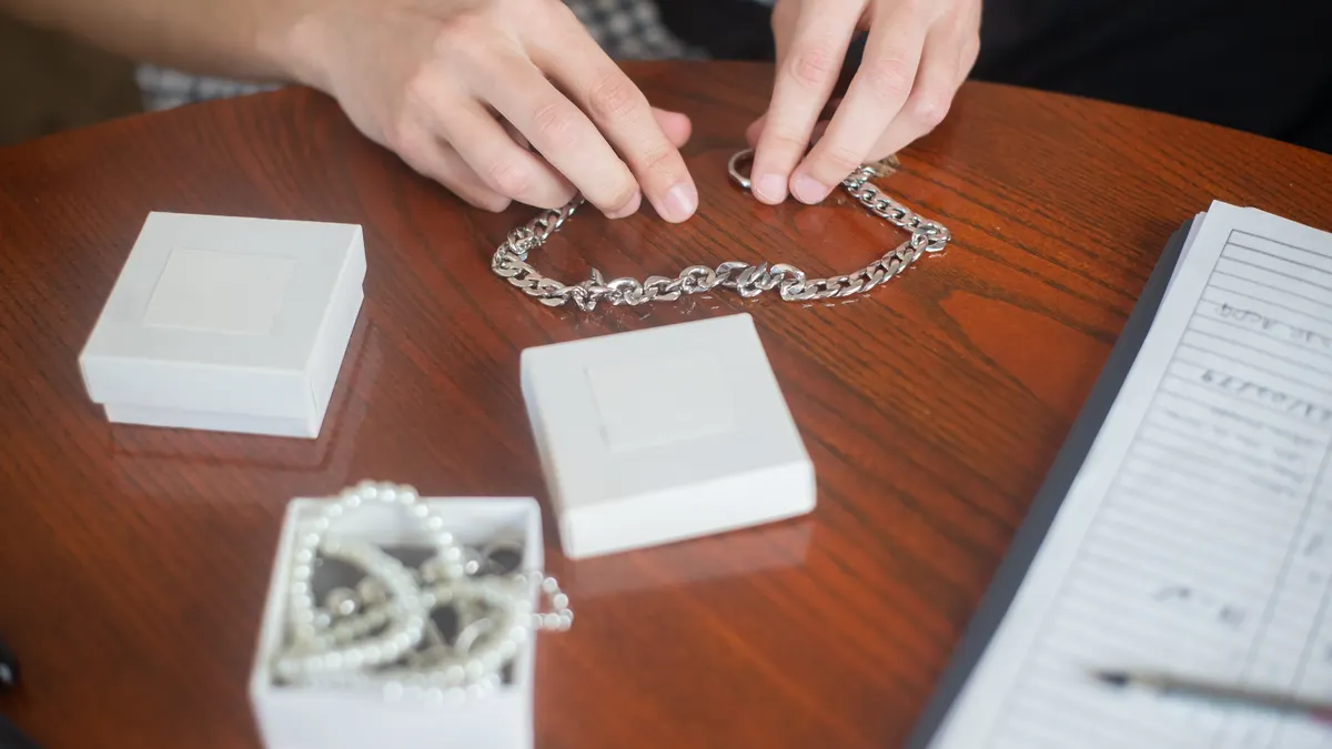 Hands arranging a necklace chain on a table
