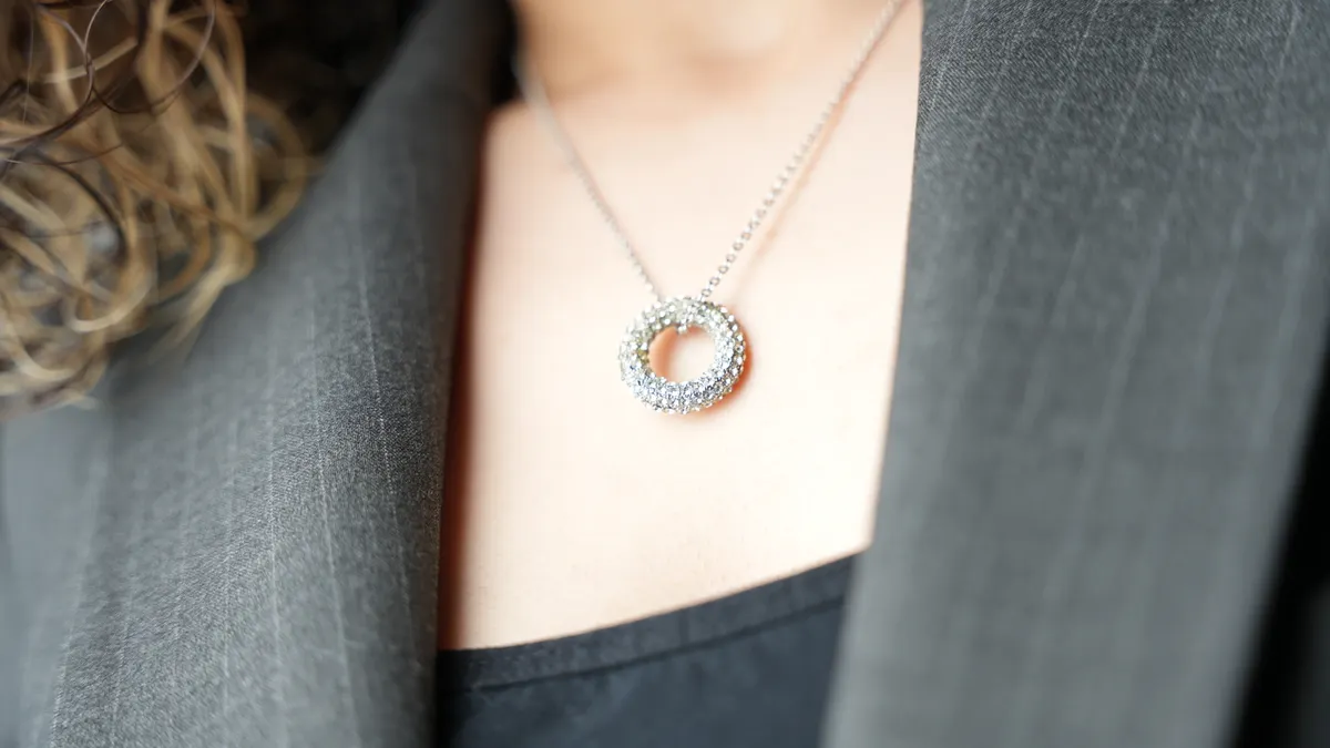 Small circular pendant necklace worn on a person